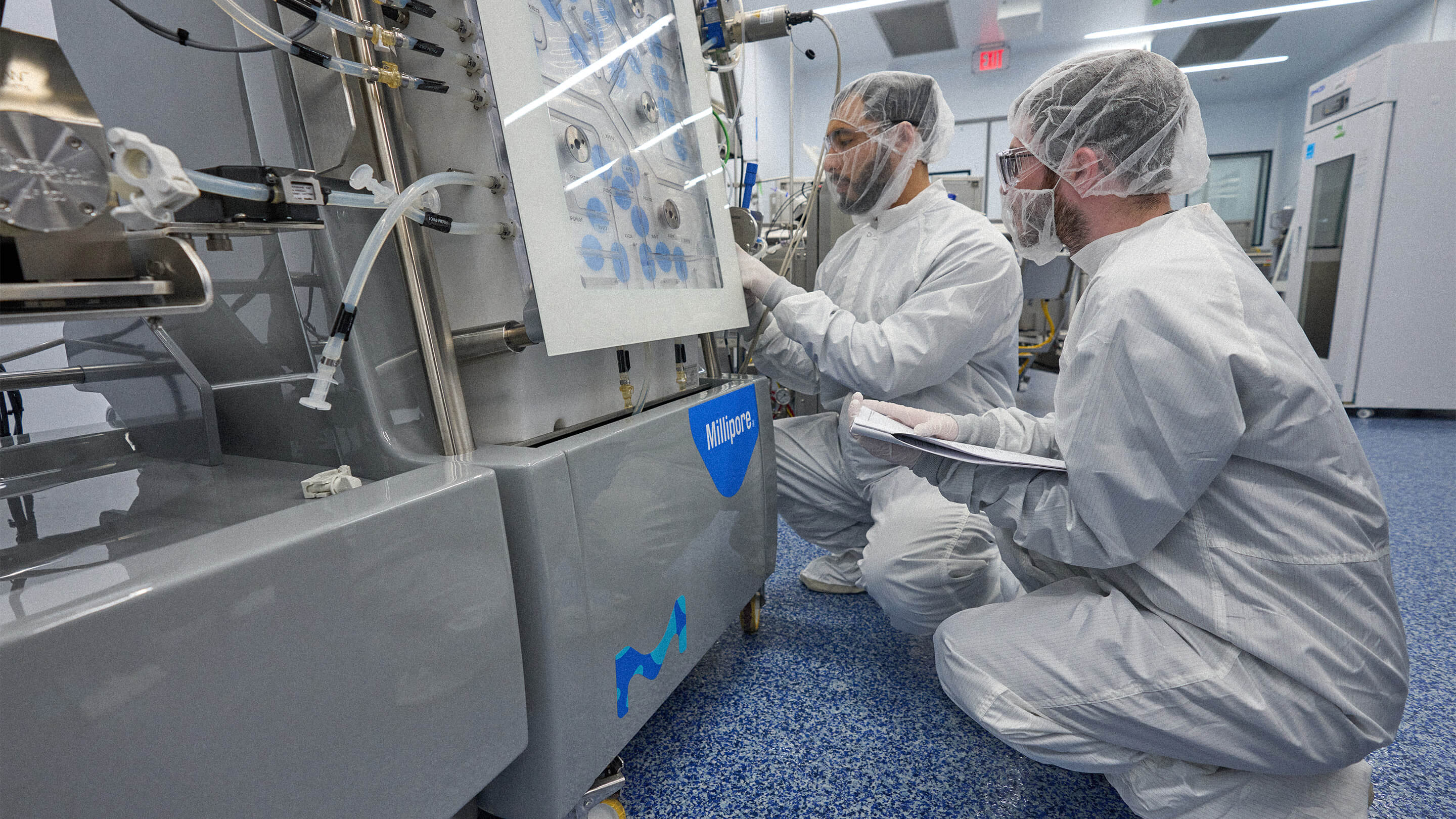 Two men in scrubs checking a lab machine